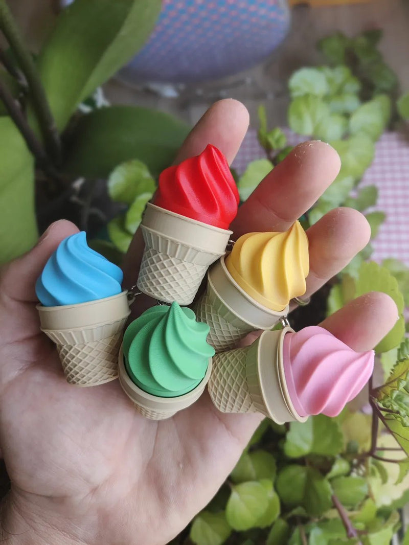 Five ice cream cone keychain clickers in soft serve colors held in a hand